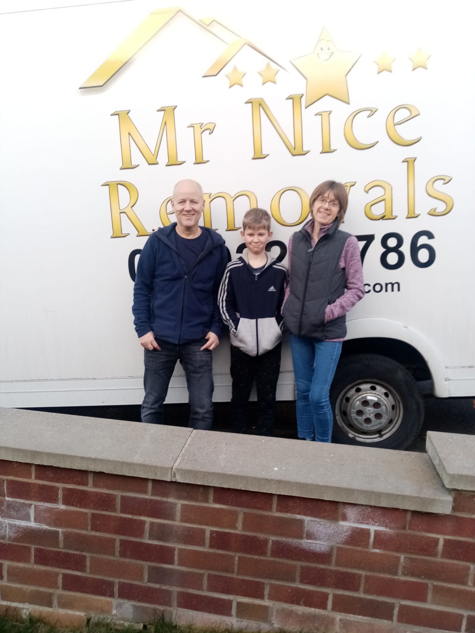 A family standing in front of a moving truck.