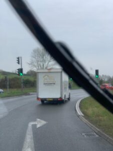 A truck driving down the road with traffic lights in the background.